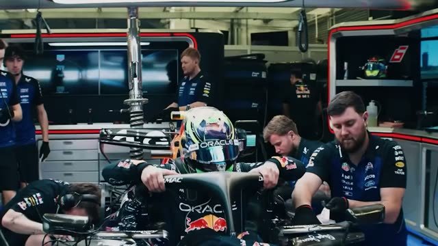 Ферстаппен в кокпите Red Bull в гараже, механики вокруг болида